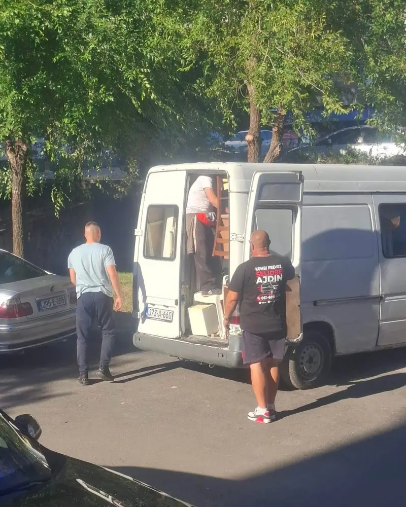 Dvojica radnika unose stvari u bijeli kombi