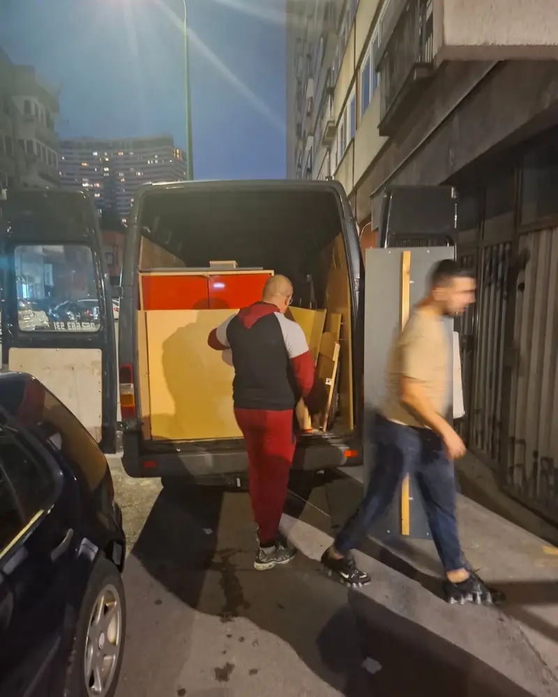 Radnici nose namještaj do kombija u uskoj ulici