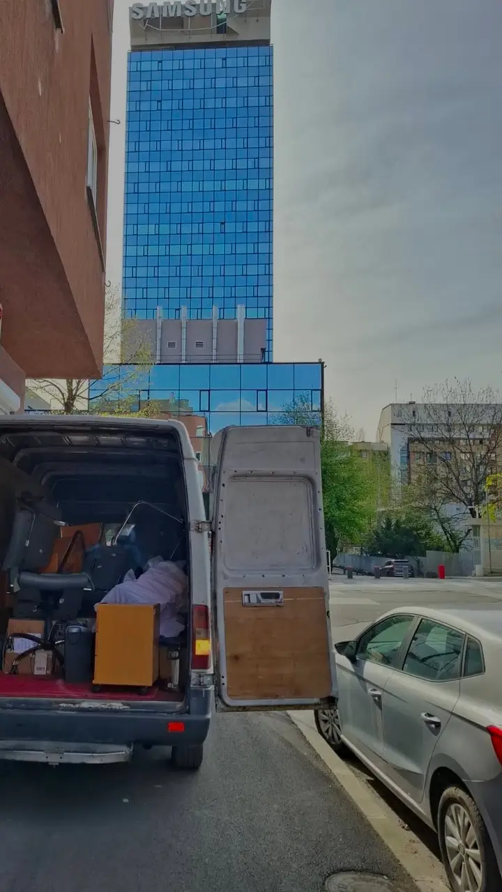 Natovaren kombi ispred zgrade u Sarajevu, iza se vidi Avaz Twist Tower