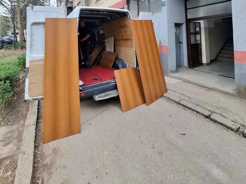 Utovar drvenih ploča namještaja u kombi ispred zgrade